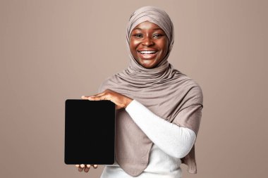 Uygulamayı kontrol et. Türbanlı Afrikalı Müslüman Kadın 'ın Ellerinde Siyah Ekran olan Dijital Tablet, Sırıtkan İslamcı Kadın Tasarımınız için Kopyalama Alanıyla Aygıt Gösterimi