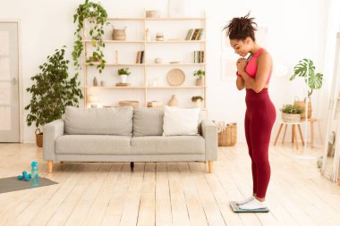 Mutlu siyah kız kilosunu tartıyor evde ayakta durarak kilo kaybediyor. Metin için Tam Uzunluk, Boş Boşluk