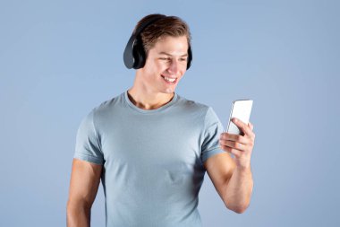Akıllı telefonlu genç sporcu Violet stüdyosunun arka planında müzik dinliyor. Mobil cihaz eğitimi için şarkı listesini seçen yeni nesil sporcunuz kutlu olsun.