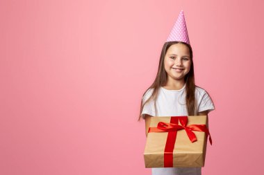 Benim için mi? Hediye kutusundaki küçük kız ve büyük, pembe arka planda izole edilmiş, boş alan.