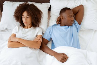 Yatakta sorunlar, kavga, dargınlık, aile ilişkileri ve olumsuz duygular. Genç Afro-Amerikalı karı ve kocayı kırdım. Ellerini çapraz yapıp birbirlerini görmezden geldiler. Yatak odasında, üst tarafta, fotokopi odasında.