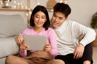 Çinli Eşler Evdeki Zeminde Oturan Dijital Tablet Bilgisayarla Online Film İzliyor. Haftasonu Gevşemesi, Çevrimiçi Film Oynatıcı Uygulaması.