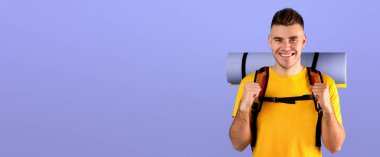 Turist vitesli neşeli genç adam mavi stüdyo geçmişi üzerinden EVET işareti yapıyor. Bin yıllık olumlu yürüyüşçü yolculuğundan heyecan duyuyor, kamp gezisi ya da macera bekliyor.