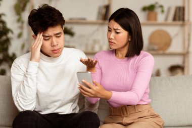 İlişkide sadakatsizlik var. Kıskanç Asyalı Eş Aldatan Koca 'nın Evdeki Kanepede Otururken Açıklama İsteğini Gösteriyor. Sadakatsiz Erkek Arkadaştan Şüphelenen Kız Arkadaşının Başka Bir Kadınla İlişkisi Var.