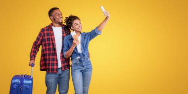 Tatil Gezisi Selfie 'si. Afrikalı Amerikalı Gezginler, Smartphone Holding uçuş biletlerinde Selfie Çekiyor. Sarı Stüdyo 'nun arka planında bavulları duruyor. Seyahat ve Turizm Konsepti