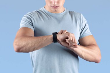 Güçlü atletik adam menekşe stüdyosundaki ukalalığına bakıyor. Formda genç adam antrenman sırasında takip cihazını kontrol ediyor. Modern teknolojiler ve sağlıklı yaşam tarzı kavramı