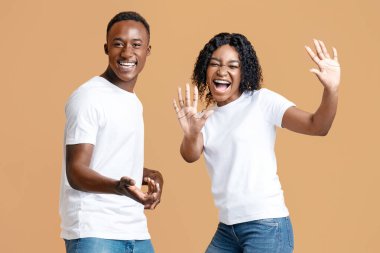 Duygusal Afrikalı Amerikalı erkek ve kadın, sarı stüdyo arka planında fotokopi çekerek dans edip şarkı söylüyorlar. Neşeli siyah aşıklar birlikte eğleniyorlar, müzik dinliyorlar, hareket ediyorlar ve çığlık atıyorlar.