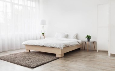 Basit modern yatak odası iç tasarımı, çağdaş minimalist tasarım. Yastıklı ve battaniyeli çift kişilik yatak, yerde halı, büyük perdeli pencere, beyaz duvarlı arka plan, kopyalama alanı, hiç kimse