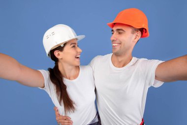 Koruyucu Şapkalı Neşeli Çiftin Birlikte Selfie Çekmesi, Ev Yenileme sırasında Eğlenmesi, Neşeli Erkek ve Kadın Tamircileri Mavi Bakırlık 'ta poz verdirmesi,