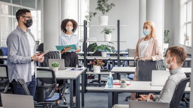 Karantinadan sonra müdürle görüşüp sağlığını korumak. Koruyucu maskeli ve tabletli patron ofisteki çok ırklı işçilere konuşuyor. Cihazlarla, boş alanlarla iç içe.