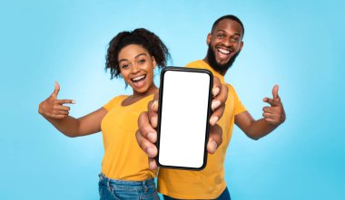 Bu yeni mobil uygulamayı kullan. Neşeli Afro-Amerikan çift boş beyaz ekranla akıllı telefonu işaret ediyor, web sitenizin reklamını yapıyorlar, maket yapıyorlar. Seçici odaklanma. Pankart tasarımı