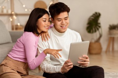 Japon Milenyum Çifti Dijital Tablet Bilgisayar kullanarak Evde Birlikte Oturarak Hafta Sonu Akşamı 'nı Birlikte Geçiriyor. Web sörfü, Modern Gadgets Yaşam Tarzı Konsepti