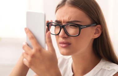 Zavallı görme duyusu. Smartphone Screen 'e bakan şaşı gözlü kız içeride oturuyor. Seçici Odaklanma