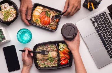 Online teslimat. Ofiste sağlıklı gıda öğle yemeği zaman sahip iki collegues, kopya alanı ile cep telefonu