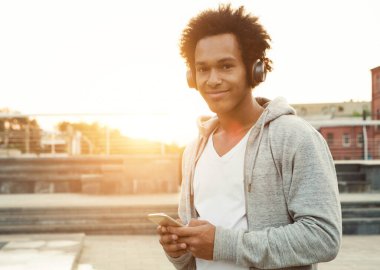 Afro-Amerikan Teenage Boy Müzik Dinleme Ve Kentsel Ortamda Telefon Kullanma, Yaz Akşamı Yürüyüş, Sunlight Flare, boş alan