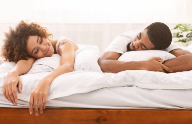 Rahatlama zamanı. Mutlu, yorgun, Afrikalı sevgili yatakta dinleniyor.