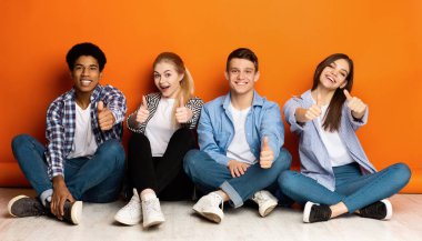 Eğitim konsepti. Turuncu arka planda başparmak gösteren mutlu öğrenci takımı