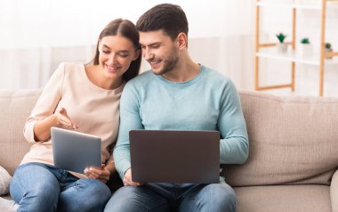 Gadget Yaşam Tarzı. Erkek arkadaş, dizüstü bilgisayarı ve tablet bilgisayarı olan kız arkadaş evdeki koltukta oturup interneti kolaçan eden. Seçici Odaklanma