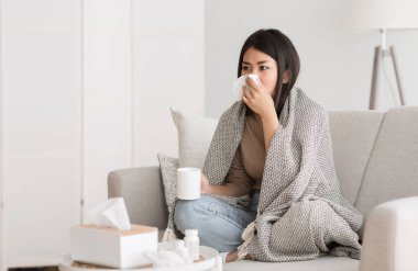 Grip ve grip. Burnu akan, sıcak çay içen ve evde televizyon izleyen hasta bir kız.