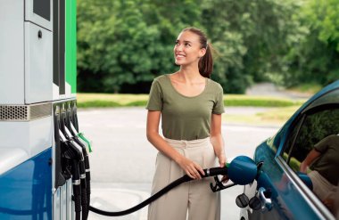 Modern Benzin İstasyonu 'nda arabasını dolduran mutlu genç kadın. Memnun Sürücü Kadın Silah deposunun yanında duruyor Araç Biyolojik Yakıt Yakıtını Biyolojik Yakıt Tüpü ile Dolduruyor