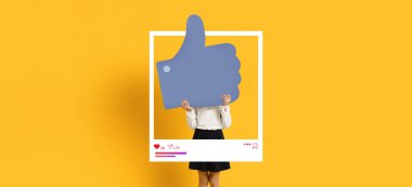 Bir kişi, sosyal medyada onay ve nişanı simgeleyen büyük bir başparmağın arkasında duruyor..