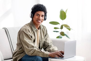 Ev konseptinden ders çalışıyorum. Bilgisayarda öğretmenle iletişim kurarken kameraya bakan kulaklıklı yakışıklı bir genç. Havalı Afro-Amerikan gençliği ödevlerini internet üzerinden hocasına gönderiyor.