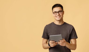 Yakışıklı öğrenci blogcusu evde kendini izole etme üzerine çalışıyor. Akıllı saat gözlüklü neşeli genç erkek dijital tablet tutuyor ve blog okuyor ya da internette sörf yapıyor.