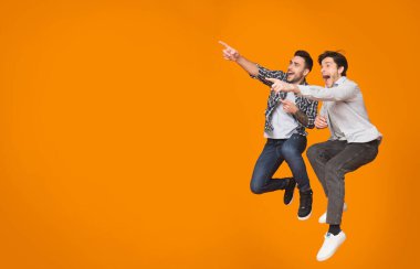 Overjoyed çocuklar boş alan işaret ve turuncu stüdyo arka plan üzerinden atlama