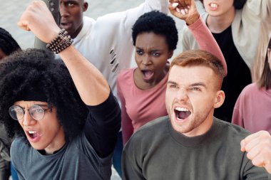 İklim değişikliği protesto konsepti. Sokaklarda grev yapan, sloganlar atan, yumruklarını kaldıran, devletin gezegeni kurtarmasını isteyen, kirliliği azaltan uluslararası bir grup insanın en üst düzey görüşü.