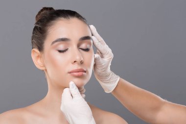 Plastik cerrahi kavramı. Genç kadın güzellik uzmanı, gri arka plan da istişare