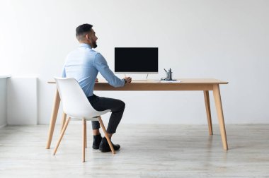 Boş bilgisayar ekranına bakan Orta Doğulu işadamının arka plan portresi işyerinde masasında oturuyor, webinar izliyor ya da internet üzerinden video görüşmesi yapıyor, ücretsiz fotokopi alanı afişi yapıyor.