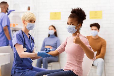 Covid-19 Aşılama. Siyahi Kız Coronavirus Aşısı Alınıyor Hastanede, Tıbbi Tedaviyi Onaylayan İşaret Ediyor. Corona Virüs Koruma, Tedavi ve İlaç. Seçici Odaklanma