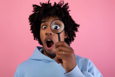 Pembe stüdyo arka planındaki büyüteçten bakan şoke olmuş genç adam. Bir şeyden şüphelenen, soruşturan ya da sorgulayan Afrikalı Amerikalı bir ergen. Sır, şüphe kavramı