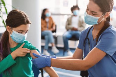 Coronavirus antiviral aşı enjekte edildikten sonra Corona Virüsü 'ne karşı aşı olan kadın doktor maske takarak Sağlık Merkezi' nde oturuyor.