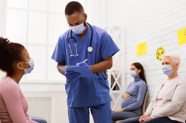 Covid-19 Aşılama. Siyah erkek hemşire Coronavirus aşısı aşısı yapılmadan önce hasta kızla konuşuyor. Corona Virüs Koruma ve Nüfus Bağışıklığı Kampanyası