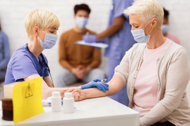 Coronavirus aşısı. Kıdemli Bayan Covid-19 Aşısını Klinik Odasında Hemşire ile Oturarak Aldı. Corona Virüs Tıp, Tedavi ve Nüfus Bağışıklığı Konsepti. Seçici Odaklanma