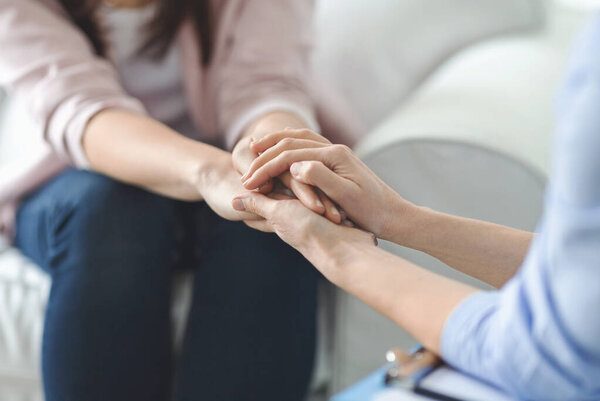Одиночество, отчаяние, депрессия. Крупным планом психолог трогает женские руки, специалист утешает грустную женщину
