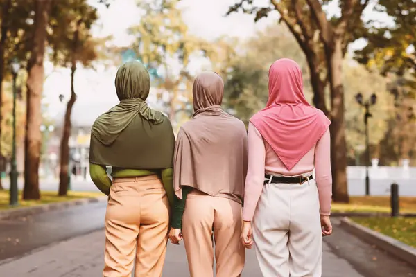 Şehir parkında türban takan üç modern Müslüman kadının arka planda görüntüsü. İslam Kadınları Dostluğu ve Arap Moda Kavramı