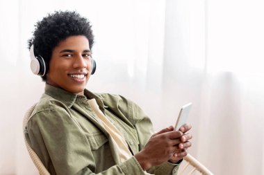 Evde cep telefonundan müzik listesi seçen kulaklıklı yakışıklı siyah ergen. Havalı Afro-Amerikalı genç adam en sevdiği şarkıyı dinliyor, sesli kitap ya da radyo.
