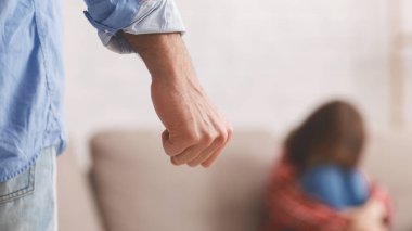 Çocuklara karşı şiddet. Öfkeyle yumruk sallayan bir adam, arka planda ağlayan küçük bir kız, boş alanı olan bir panorama