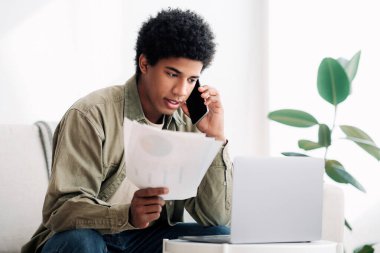 Ciddi siyahi genç adam evden online ders çalışıyor, özel hocasıyla akıllı telefon ödevi hakkında konuşuyor. Afrika kökenli Amerikalı üniversite öğrencisi öğretmeniyle eğitim projesini tartışıyor.