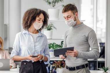 İş ve koronavirüs salgınına karşı koruma fikirleri. Müdürün dediğine göre koruyucu maske tabletindeki Afro-Amerikan kadın iş yerine yakın bir yerde dizüstü bilgisayar ve bir şişe antiseptik kullanıyor.