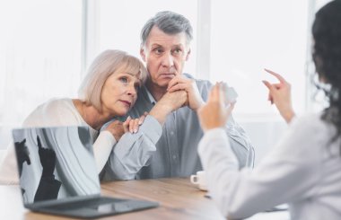 Reçete konsepti. Kadın doktor elinde ilaç kavanozuyla ofisteki üzgün yaşlı çifte talimat veriyor.