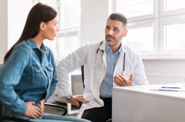 Erkek tıp uzmanı kadın hasta, karın ağrısından şikayetçi, karın ağrısı, pankreas iltihabı, mide iltihabı ya da ishal nedeniyle karın ağrısı çeken kadın.