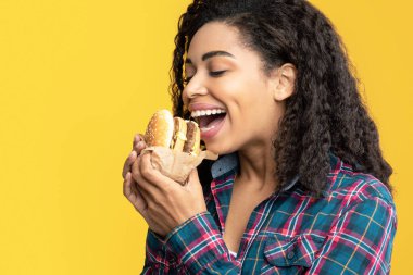 Lezzetli çerez. Aç Siyah Kadın Modeli Hamburger 'in Yakın Çekim Portresi. Afro-Amerikalı Kadın Lezzetli Fast Food tutuyor, Portakal Stüdyosu Arkaplanı, Afişi, Kopyalama Alanı