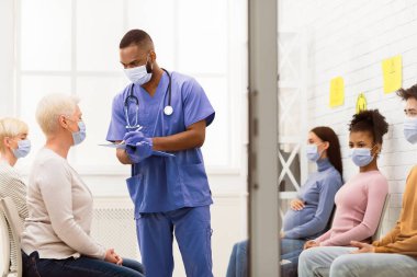 Coronavirus aşısı. Doktor, yaşlı hasta ile konuşurken not alıyor. Hastahane bekleme odasındaki aşı aşısından önce. Corona Virüs Salgını, Tıbbi Tedavi Konsepti