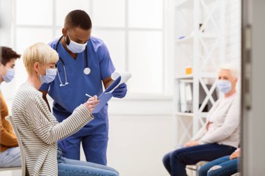 Hasta kadın Coronavirus aşısından önce doktorla evrakları imzalıyor. Hastanenin bekleme odasında bekliyor. Covid-19 Salgın Tıbbi Tedavi Konsepti. Metin için Boşluk