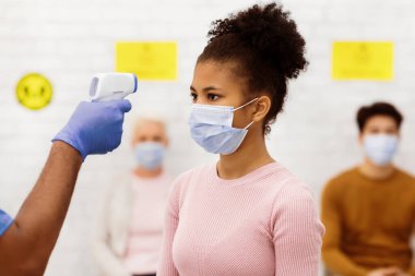 Hasta genç kız için Sıcaklık taraması yapan bir tıp işçisi. Klinikteki Doktor Randevusundan Önce Ateşi Ölçüyor. Temassız Kızılötesi Themometer kullanıyor. Coronavirus Koruması Hastanede