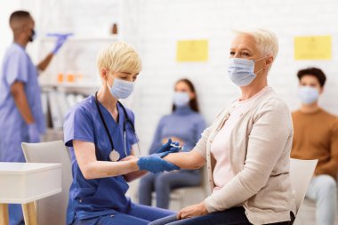 Corona Virüs Aşısı. Kovan 19 aşısı olan olgun bir kadın hastanede hemşireyle otururken koluna iğne vuruluyor. Coronavirus İmmün Kampanyası, Covid 19 İlaç ve Tedavi Konsepti