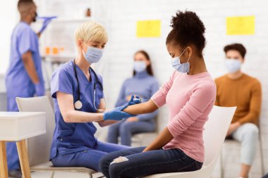 Coronavirus aşısı. Corona Aşısı Enjeksiyonu 'na karşı Aşı Yapan Afrikalı Genç Kız Kolunda Otururken Hastanede. Covid 19 Virüs Bağışıklık Kampanyası